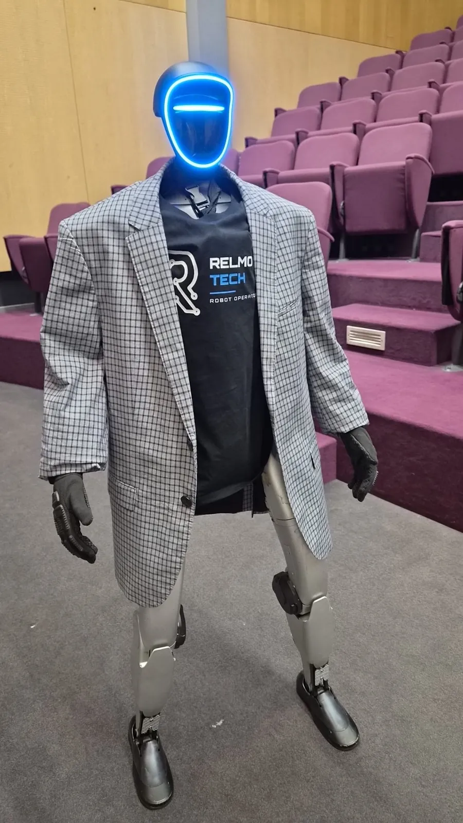 RELMO in een geruite blazer en RELMO Tech-shirt in een auditorium